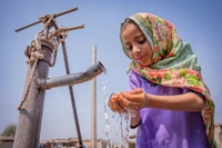 Một cô bé đang uống nước từ máy bơm tay tại Pakistan. Nguồn: UN