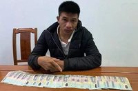 Đối tượng Đoàn Văn Dương với số tiền giả mà cơ quan chức năng thu giữ. (Ảnh: Công an cung cấp)