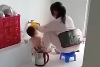 Hình ảnh bảo mẫu đổ thức ăn vào miệng trẻ lan truyền trên mạng xã hội. (Ảnh: Cắt ra từ clip)