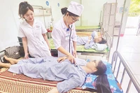 Các thầy thuốc Trung tâm Y tế huyện Sông Lô thăm khám cho bệnh nhân. 