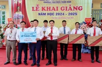 Phó Thủ tướng Lê Thành Long (phải) tặng 5 bộ máy vi tính cho Trường tiểu học và trung học cơ sở Tuân Đạo, huyện Lạc Sơn.