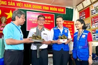 Đồng chí Nguyễn Phước Lộc, Phó Bí thư Thành ủy, Chủ tịch Ủy ban Mặt trận Tổ quốc Việt Nam Thành phố Hồ Chí Minh (bên trái) trao bánh giò mới nấu đến cán bộ, chiến sĩ trên nhà giàn DK1/10.