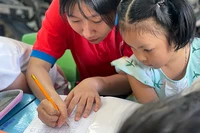 Chiến sĩ "Hoa phượng đỏ" dạy trẻ em có hoàn cảnh khó khăn học chữ, đánh vần trong những ngày hè vừa qua. (Ảnh: Trung ương Hội Sinh viên Việt Nam cung cấp)