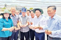 Tỷ phú nông dân Lê Văn Sấm (hàng đầu, thứ 2 từ trái sang) giới thiệu về tôm nuôi tại trang trại.