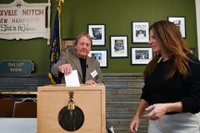 Nhân viên điều phối giúp một nữ cử tri (bìa phải) bỏ phiếu tại Dixville Notch, New Hampshire trong ngày bầu cử tổng thống Mỹ, 5/11/2024. (Ảnh: Xinhua)