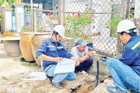 Nhân viên Xí nghiệp cấp nước Cần Giờ gắn đồng hồ nước thông minh thay cho đồng hồ cũ cho các hộ dân tại xã Tam Thôn Hiệp, huyện Cần Giờ.