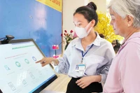 Cán bộ phường Bến Nghé, Quận 1 hướng dẫn người dân thực hiện đăng ký hồ sơ trực tuyến. (Ảnh: THẾ ANH)