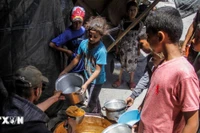 Trẻ em nhận thức ăn cứu trợ tại trại tị nạn ở Jabalia, Dải Gaza. (Ảnh: THX/TTXVN)