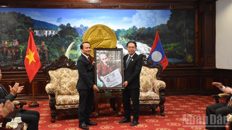 Phó Bí thư Thường trực Thành ủy Đà Nẵng Nguyễn Đình Vĩnh trao tặng bức ảnh Bác Hồ đọc Báo Nhân Dân cho đồng chí Bí thư Tỉnh ủy Salavane Daovong Phonekeo. (Ảnh: ANH ĐÀO) ndo_br_dsc-8055-320.jpg