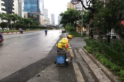 Công nhân Công ty Thoát nước Hà Nội vệ sinh các miệng thu nước trên đường Nguyễn Chí Thanh. (Ảnh: CẢNH HOÀNG)