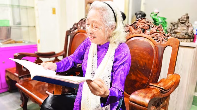 Bà Hoàng Thị Thanh xem lại những tư liệu xưa. (Ảnh: MẠNH HẢO)