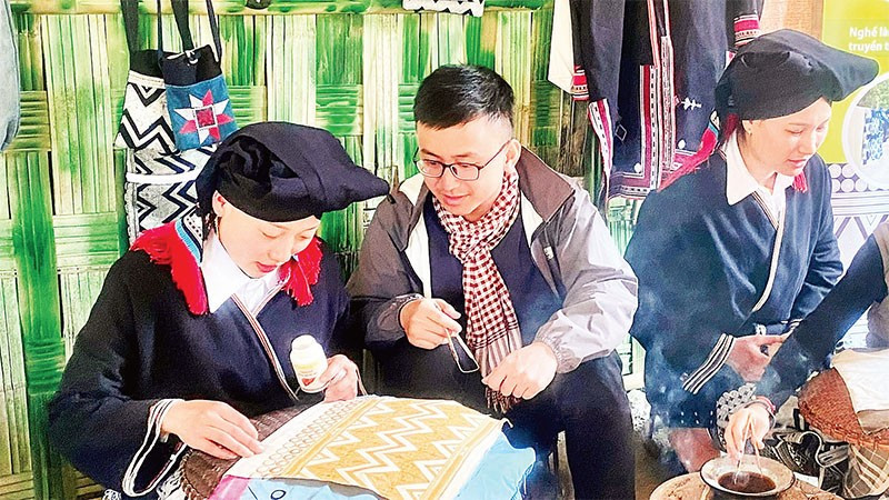 Du khách trải nghiệm nghề truyền thống vẽ sáp ong tại điểm du lịch cộng đồng bản Sưng, xã Cao Sơn.