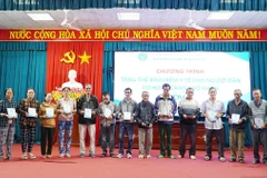 Phó Giám đốc Bảo hiểm xã hội tỉnh Trần Ngọc Tuấn cùng các đại biểu trao tặng thẻ bảo hiểm y tế cho người dân. (Ảnh: BTC)