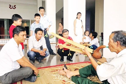 Nghệ nhân Ama Hloan ở buôn Akô Dhông, phường Buôn Ma Thuột, tỉnh Đắk Lắk giới thiệu nhạc cụ Đinh Năm với du khách.