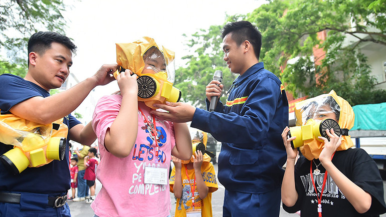 Cán bộ, chiến sĩ Trường đại học Phòng cháy chữa cháy hướng dẫn các gia đình sử dụng mặt nạ cứu hỏa đa năng Chance E và trải nghiệm mô hình thoát hiểm nhà khói. (Ảnh MỸ HÀ)