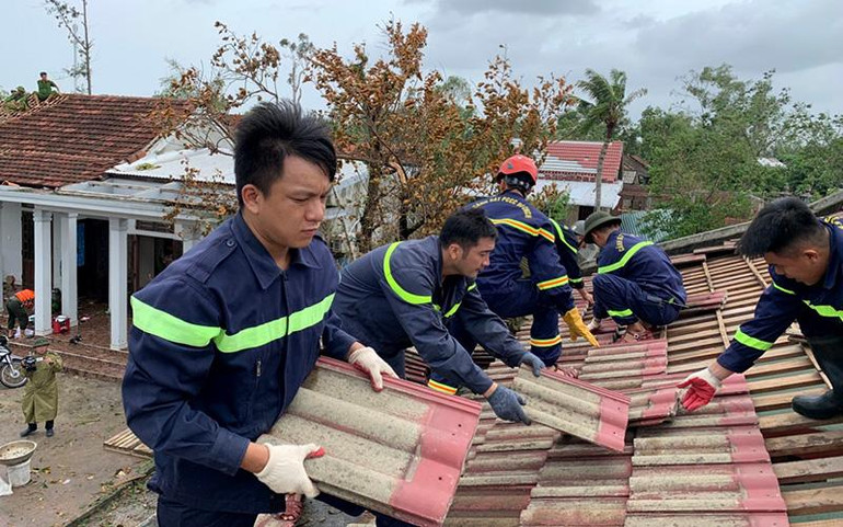 Lực lượng chức năng giúp dân lợp lại nhà bị tốc mái tại thôn Mai Vĩnh, xã Vinh Xuân, huyện Phú Vang, tỉnh Thừa Thiên Huế. (Ảnh CÔNG HẬU)