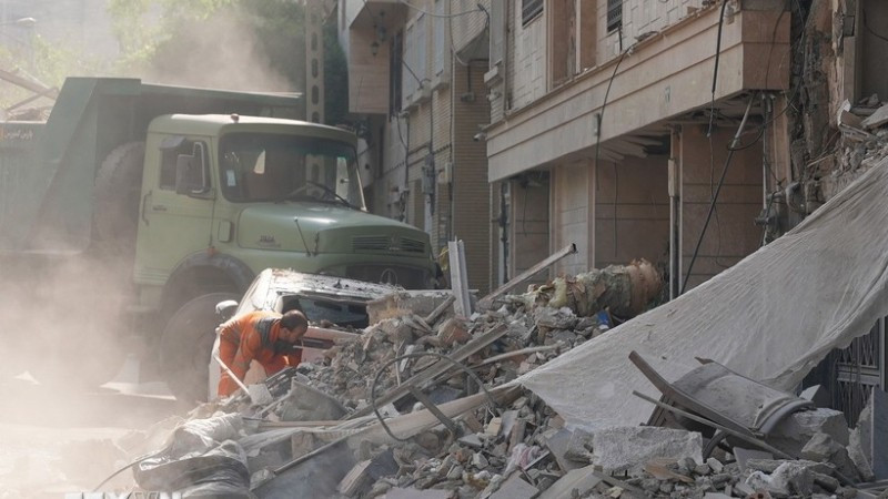 Nhân viên cứu hộ dọn đống đổ nát của tòa nhà bị sập tại Tehran, Iran sau các cuộc không kích của Israel. (Ảnh: THX/TTXVN)