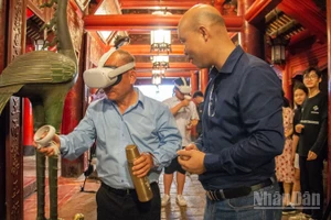 Khách du lịch thích thú khi được trải nghiệm hệ thống thực tế ảo tại di tích Văn Miếu-Quốc Tử Giám. (Ảnh: HÀ NAM)