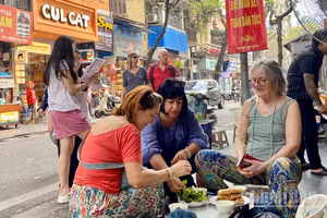 Khách quốc tế thưởng thức ẩm thực đường phố khi tham quan Hà Nội. (Ảnh: CHIÊU ANH)