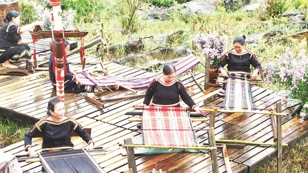 Người phụ nữ Ê Đê bên khung dệt vải thổ cẩm.