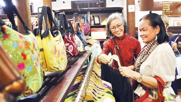 Khách du lịch mua hàng tại một cửa hàng giới thiệu sản phẩm làng nghề dệt lụa Vạn Phúc.