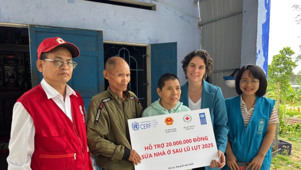 Đại diện Chương trình Phát triển Liên hợp quốc (UNDP) trao tiền hỗ trợ cho gia đình bị ảnh hưởng bởi bão lũ.