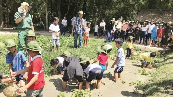 Các em học sinh trải nghiệm hoạt động bắt cá tại Địa đạo Củ Chi. (Ảnh MẠNH HẢO)