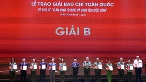 Đồng chí Lê Quốc Minh, Uỷ viên Trung ương Đảng, Phó Trưởng Ban Tuyên giáo và Dân vận Trung ương, Tổng Biên tập Báo Nhân Dân, Chủ tịch Hội Nhà báo Việt Nam và Thượng tướng Trần Quốc Tỏ, Uỷ viên Trung ương Đảng, Thứ trưởng Bộ Công an trao giải Nhì cho các tác giả, đại diện nhóm tác giả. Ảnh: TUẤN ANH/TTXVN