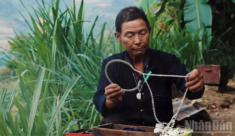 Nghệ nhân Nùng Văn Sính kiểm tra dây bạc lớn sau khi hoàn thiện công đoạn chế tác tại Pờ Ly Ngài. ndo_br_nghe-nhan-gia.jpg