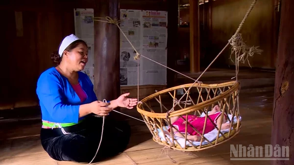 Người mẹ Mường dịu dàng ru con ngủ bên chiếc nôi tre.