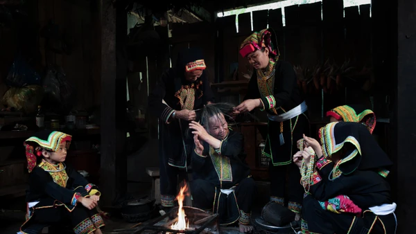 Bà Bàn Minh Toan cùng các phụ nữ Dao Lù Gang quây quần bên bếp lửa thực hiện công đoạn sơn đầu, trong không gian sinh hoạt đậm chất cộng đồng.