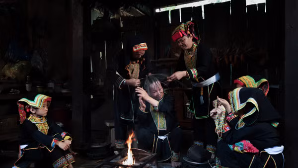 Bà Bàn Minh Toan cùng các phụ nữ Dao Lù Gang quây quần bên bếp lửa thực hiện công đoạn sơn đầu, trong không gian sinh hoạt đậm chất cộng đồng.