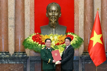 Chủ tịch nước Lương Cường trao quyết định và tặng hoa chúc mừng đồng chí Nguyễn Trọng Nghĩa. (Ảnh: THỦY NGUYÊN)