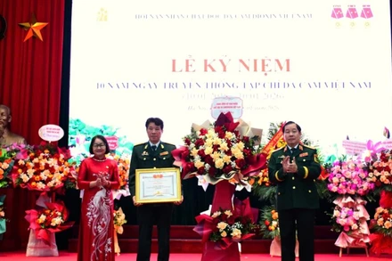 Trung tướng Nguyễn Hữu Chính tặng hoa chúc mừng và trao Bằng khen của Trung ương Hội Nạn nhân chất độc da cam/dioxin Việt Nam cho Tạp chí Da cam Việt Nam. 