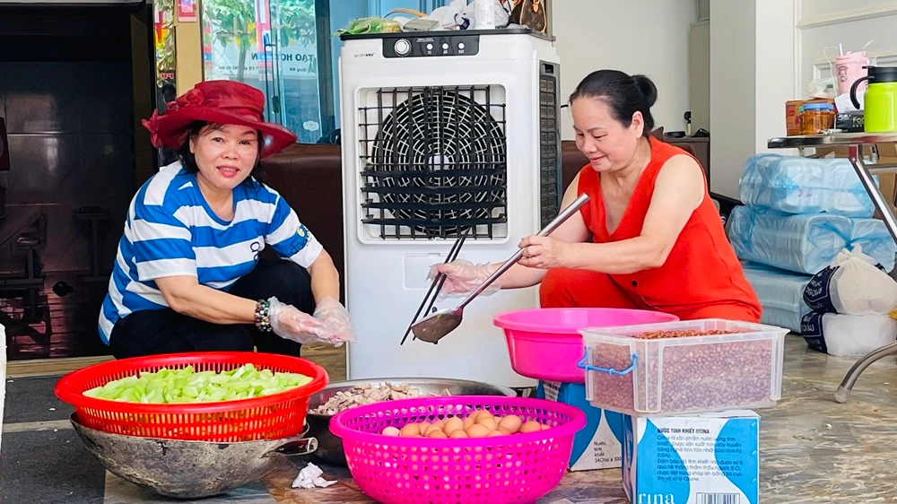 Bà Lý (bìa trái) tham gia chia khẩu phần thức ăn phục vụ bữa trưa 18/9. (Ảnh: THANH SƠN)