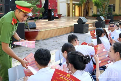 Cán bộ Công an tỉnh Cà Mau phát tờ rơi tuyên truyền nâng cao nhận thức pháp luật trên không gian mạng cho học sinh Trường trung học phổ thông chuyên Phan Ngọc Hiển.