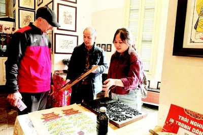 Võ Ca Dao hướng dẫn cho du khách nước ngoài trải nghiệm in tranh mộc bản.