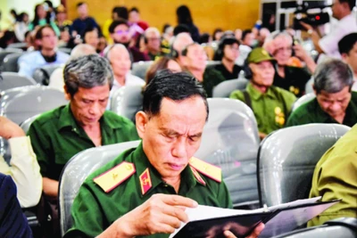 Thiếu tướng Trịnh Xuân Chuyền đọc những dòng chữ trong hồ sơ của đồng đội được trao trả. (Ảnh GIA KHÁNH)