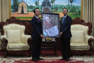 Phó Bí thư Thường trực Thành ủy Đà Nẵng Nguyễn Đình Vĩnh trao tặng bức ảnh Bác Hồ đọc Báo Nhân Dân cho lãnh đạo tỉnh Savannakhet. (Ảnh: ANH ĐÀO)