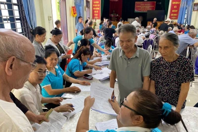 Hội Phụ nữ xã Ô Diên hướng dẫn người dân khai hồ sơ trợ cấp bảo hiểm xã hội. (Ảnh: DIỆU THƯƠNG)