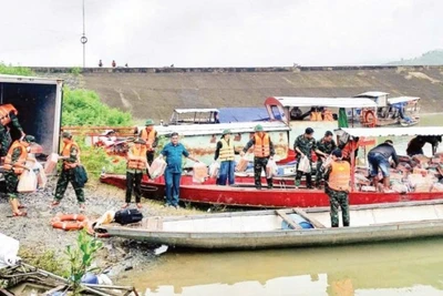 Các lực lượng chức năng xã Trà Đốc xếp lương thực, nhu yếu phẩm lên thuyền để vượt sông Tranh vào tiếp tế cho người dân bị cô lập.