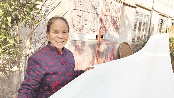 Nghệ nhân Phan Thị Thuận bên chiếc mền tơ do tằm tự dệt.