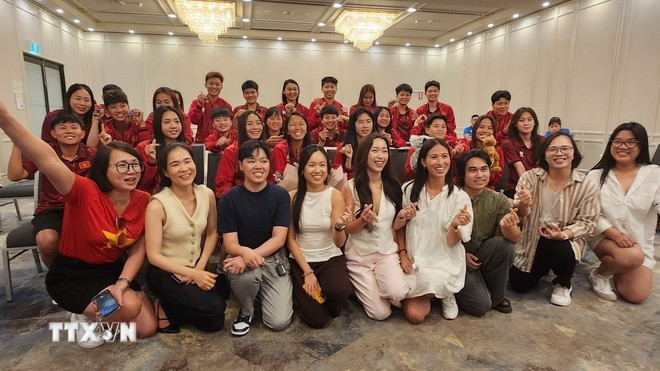 Các cổ động viên trẻ hào hứng chụp ảnh lưu niệm cùng các cầu thủ đội tuyển bóng đá nữ Việt Nam. (Ảnh: TTXVN)