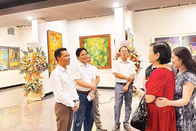 Họa sĩ Trần Giang Nam (ngoài cùng bên trái) trao đổi với người yêu tranh khắc gỗ tại triển lãm cá nhân ở Hà Nội.