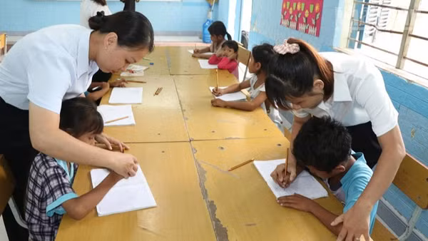 Giáo viên tại điểm trường Suối Hai, Trường tiểu học Cam Phước Đông 1, phường Ba Ngòi, tỉnh Khánh Hòa giúp các em học sinh dân tộc Raglai rèn chữ viết trên lớp học hè. (Ảnh: NGUYỄN TRUNG)