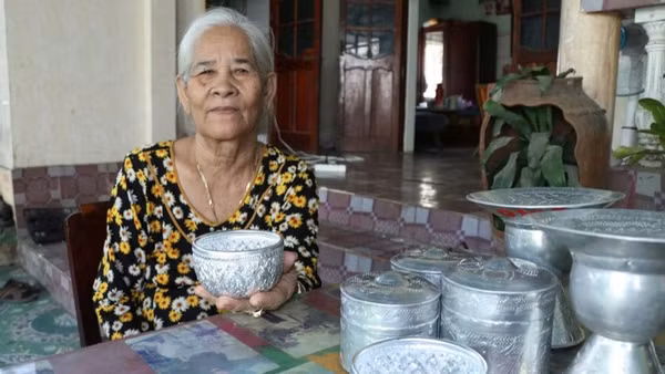 Nghệ nhân Đàng Thị Mỹ Trâm (thôn Bàu Trúc, xã Ninh Phước, tỉnh Khánh Hòa), bên những sản phẩm chạm bạc thủ công truyền thống của đồng bào Chăm. (Ảnh: NGUYỄN TRUNG)