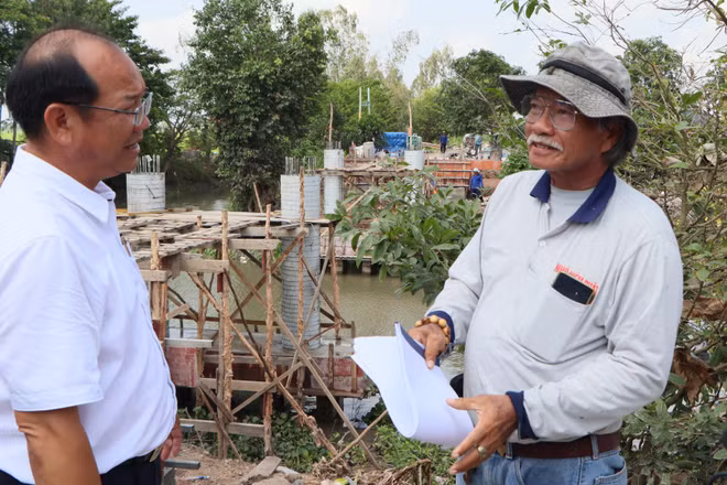 Lãnh đạo xã Châu Phú (bên trái) thăm hỏi đội xây cầu thiện nguyện.