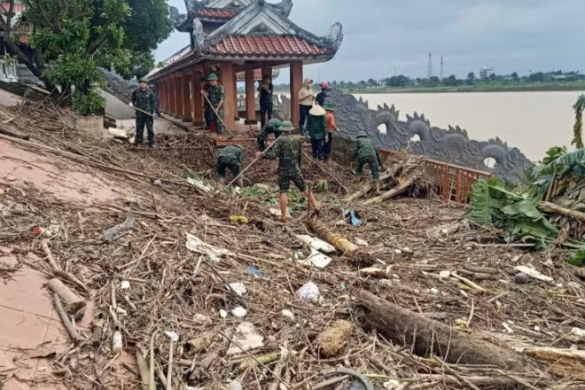 Cán bộ, chiến sĩ Ban Chỉ huy Phòng thủ Khu vực 4-Triệu Phong dọn dẹp rác và bùn tại Bến thả hoa bờ nam sông Thạch Hãn.
