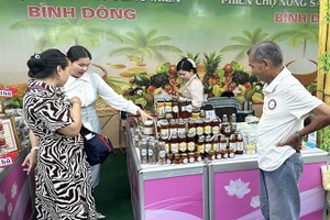 Người dân và khách tham quan tìm mua đặc sản tại một gian hàng của tỉnh Đồng Tháp trong phiên chợ.