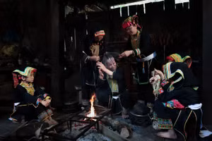 Bà Bàn Minh Toan cùng các phụ nữ Dao Lù Gang quây quần bên bếp lửa thực hiện công đoạn sơn đầu, trong không gian sinh hoạt đậm chất cộng đồng.